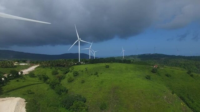 Wind turbine generators on top of green hill at Barahona. Aerial forward
