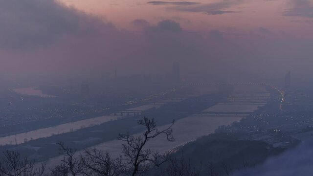 Sunrise with View over Vienna in Austria, Winter Time cold Wind, tree in Front and Donau with tall Buildings, Sun is shining