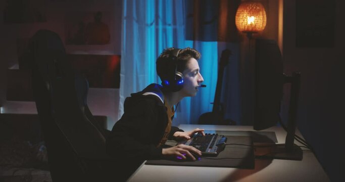 Teenage boy wearing headphones playing an online computer game, communicating with players.
His headphones out the battery, he checks what's wrong with them.