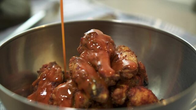Pouring hot sauce on chargrilled chicken wings