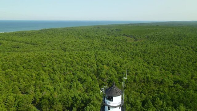 Aerial drone shot down Stilo lighthouse in Poland among thick green forest trees
