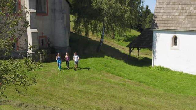 A drone shot of three hikers arrived at a white monastery at Lese, Slovenia.