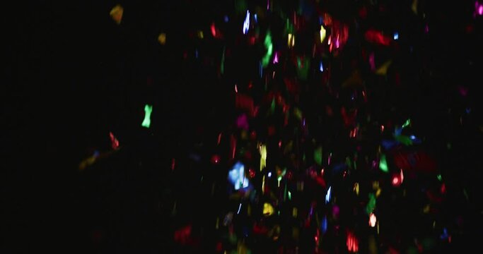 Multicoloured confetti falling on black background