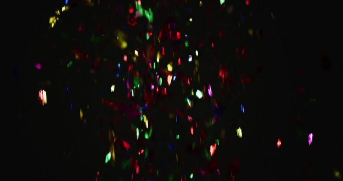 Multicoloured confetti falling on black background