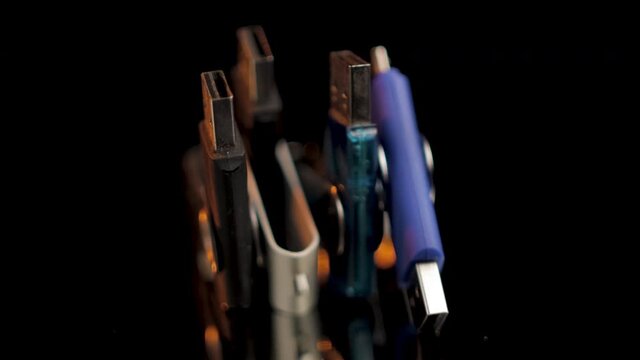 Four USB flash drives rotate on isolated black background, Closeup