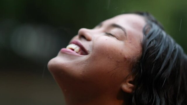 Young woman standing in rain shower outside. Girl feeling freedom raining outdoors