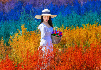 Fototapeta na wymiar Beautiful Thai woman stangding among the cutters flower in rainbow colors in Chiang Mai province, Thailand.