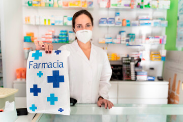 young pretty girl pharmacist with a bag whose word means "pharmacy" holding it up