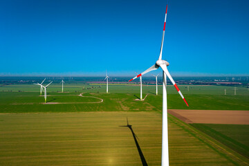 Pinwheel wind turbine on a field with another in the background and blue sky