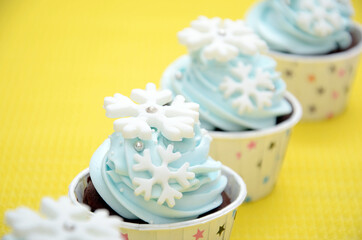 Obraz na płótnie Canvas cupcakes with frosting and topping snowflakes, happy nad fun in yellow background