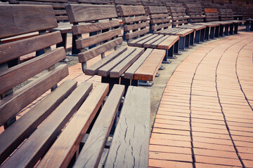 Obraz na płótnie Canvas Rows of wooden benches in the park. Benches arranged in curved lines. Toned image.