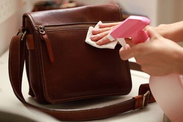 Female hand cleaning the surface of the leather bag. Coronavirus prevention, hygiene to stop...