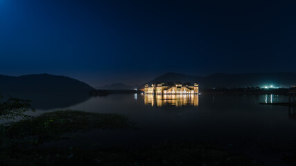 Fototapeta premium Illuminated night view of Jal Mahal 'Water Palace' is an architectural showcase of Rajput style in the Man Sagar lake in jaipur city, the capital of Rajasthan, India.