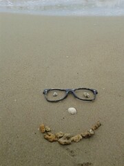 smiley face with glasses on a beach