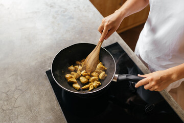 caucasian woman preparing chiken breasts , healthy meal in her rustic eco open kitchen
