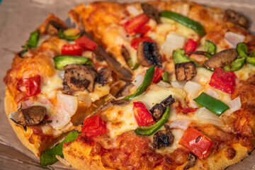 Selective focus close up of fresh cheese pizza with tomatoes, bell pepper, onions and mushrooms.
