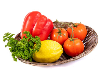 a basket of red pepper, lemon, tomatoes and parsley cooking vegetable ingredients isolated on white

