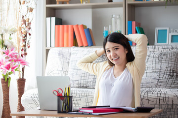 Beautiful young asian woman working on laptop computer while sitting smile, happy and relax at the living room. Business woman work at home concept.