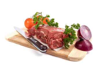 A beef sirloin roast on a wooden cutting board with onions and lemon and a parsley garnish isolated on white