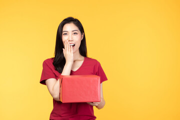 Portrait of happy smiling girl in casual holding gift box and expression face isolated over yellow background