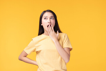 Image of feeling excited, shock, surprise and happy. Young asian woman standing on yellow background. Female face expressions and emotions body language concept.