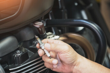 Mechanic Check Spark Plug Inspection and Maintenance, Inspection Prior to Installation in engine ignition and electrical systems at motorcycle garage.repair and maintenance concept.
