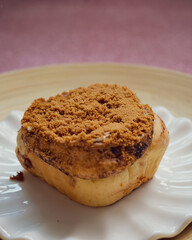 Fototapeta na wymiar Cinnamon rolls with Lotus BIscoff crumbs topping on a white and bamboo plate.