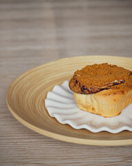 Cinnamon rolls with Lotus BIscoff crumbs topping on a white and bamboo plate.