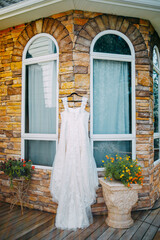 A wedding dress on the stone wall hanging during the wedding. Rustic wedding