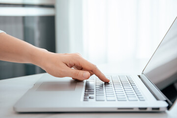 Unrecognizable woman pressing on the laptop computer keyboard by using her forefinger. 