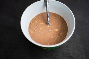 breakfast of healthy banana flakes with chocolate, oat, granola in a white bowl.