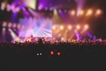 A crowded concert hall with scene stage lights, rock show performance, with people silhouette, colourful confetti explosion fired on dance floor air during a concert festival