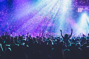 Fotobehang A crowded concert hall with scene stage lights, rock show performance, with people silhouette, colourful confetti explosion fired on dance floor air during a concert festival © tsuguliev