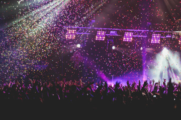 A crowded concert hall with scene stage lights, rock show performance, with people silhouette,...