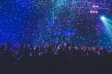 A crowded concert hall with scene stage lights, rock show performance, with people silhouette,...