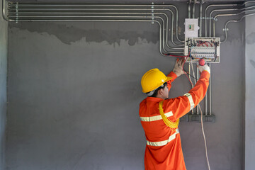 Asian electrician wear safety clothes with electric screwdriver installations and wires on relay protection system.