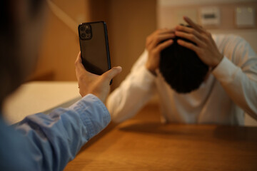 男性にスマートフォンの画面を見せる女性