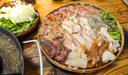 Fresh beef pork bacon squid and 
shrimp and vegetable on wood plate .Meet and vegetable shabu set.