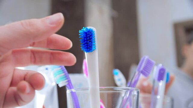 Changing toothbrush. Female hand replacing old dirty worn out tooth brush with a new one. Closeup, slow motion. Shot in 60 fps, slowed down to 24 fps.