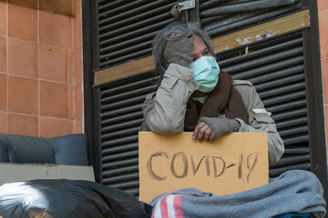 A homeless man carries a cvid-19 sign, a problem of modern megacities.