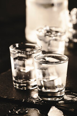 Frozen Vodka in shot glasses on black background, iced strong drink
