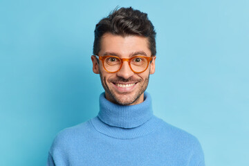 Headshot of handsome bearded with European appearance looks directly at camera smiles pleasantly...