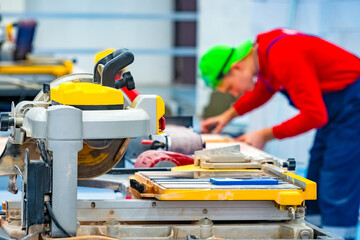 A man in a bright cap working in the Studio. Circular saw for cutting stone and tiles. Finishing work. Circular saw with water supply. Cutting natural stone. Construction equipment.