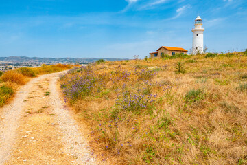 Fototapeta na wymiar Island of Cyprus. Pathos. Pafos archaeological Park. The road leads to the white lighthouse. Lighthouse in Paphos. Mediterranean landscape with a lighthouse. Cyprus on a Sunny summer day.