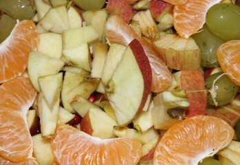 many pieces of apple, orange,green grape,banana, on the plate with food background.