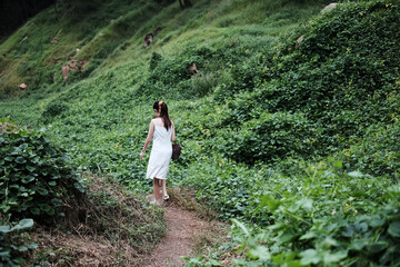 Naklejka na ściany i meble Beautiful asian female in white dress is walking in the forest.