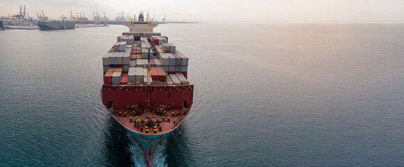 Aerial in front of cargo ship carrying container and running near international sea port for export.