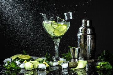 Cucumber gin and vodka alcohol cocktail. Infused summer mocktail with fresh, citrus fruit and cucumber, with liquid splash, freeze motion in jar glass on dark background