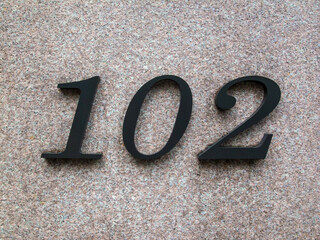 Number 102 on a marble wall. 