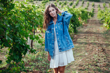 beautiful woman in white dress and denim jacket in the vineyards